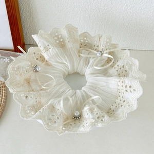 Detailed macro view of large cream white lace scrunchie with bows and pearls