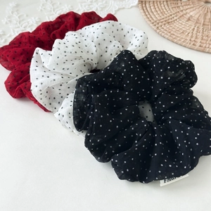 Close-up of red, white, and black polka dot scrunchies in soft chiffon fabric