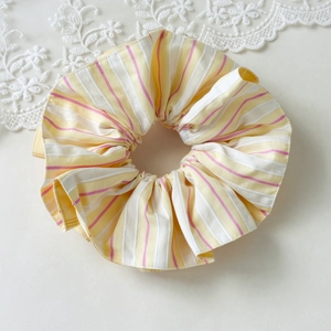 Detail of yellow and white striped fabric scrunchie with soft pastel texture