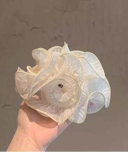 Detail of white ruffled mesh flower hair tie with a central bead for elegant styling