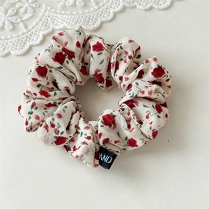 Gros plan sur chouchou fleuri avec roses rouges et étiquette sur tissu en mousseline