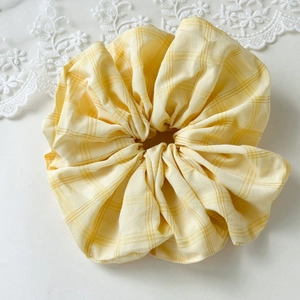 Detailed view of yellow plaid scrunchie with soft fabric texture on white background