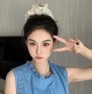 Close-up of cream white organza scrunchie styled on a voluminous high hair bun