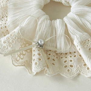 Detail of cream lace scrunchie featuring a ribbon bow with pearl and rhinestone accents