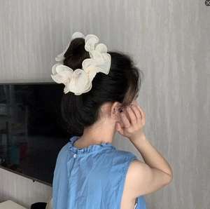 Detail showing oversized cream pleated organza scrunchie on a bun hairstyle