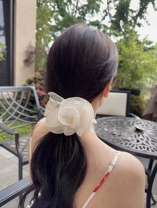 Detail of a large cream mesh flower hair scrunchie styled on a woman's long hair