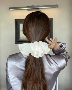 Close-up of cream oversized ruffled scrunchie with dark trim on a ponytail