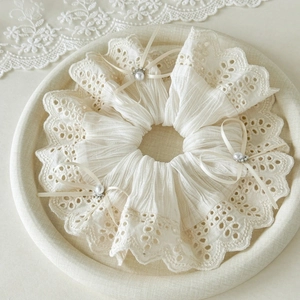 Detail of cream lace scrunchie with delicate ribbon bows and pearl rhinestone accents