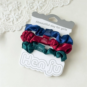 Detailansicht von drei Satin-Haargummis in Marineblau, Weinrot und Waldgrün Set