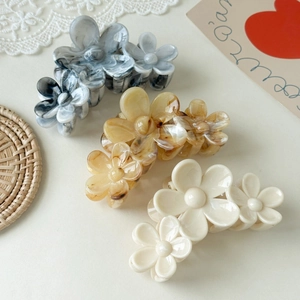 Detail of floral claw clips in amber, marble grey and cream white resin finishes