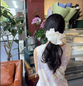 Detailed view of a white oversized pleated scrunchie styled in a low ponytail