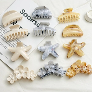 Flat lay of 11-piece hair clip set with marble and tortoise textures on white fabric
