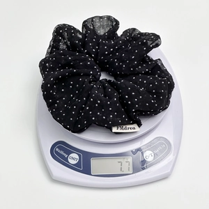 Close-up of black polka dot scrunchie on electronic scale showing 7.7g weight detail
