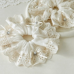 Detail of white lace hair scrunchies with elegant ribbon bows and pearl accents