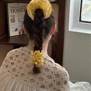 Yellow striped fabric scrunchies on long braided hair in a cozy home setting