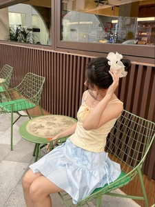 Close-up of white oversized mesh flower scrunchie on model in an outdoor cafe setting