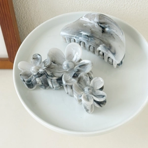 Detail view of marble pattern hair claw clips in a white ceramic dish