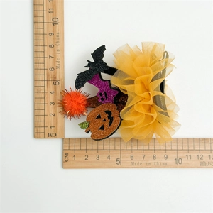 Close-up of Halloween hair accessory with glittery bat and pumpkin on yellow mesh