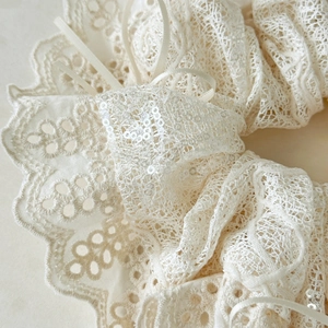 Close-up of beige lace hair scrunchie with intricate embroidery and shiny sequins detail