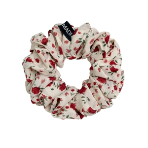 Chouchou en tissu à motifs de roses rouges et étiquette tissée sur fond blanc