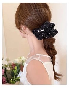 Detail of a large vintage black hair scrunchie with white polka dots on a braided ponytail