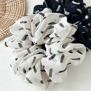 Detailed close-up of premium black and white striped chiffon scrunchies with abstract prints
