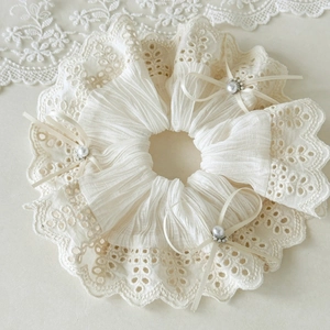 Close-up of cream lace scrunchie featuring delicate pearl bows and intricate floral edges