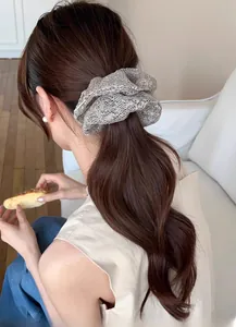 Close-up of a large silver sequin scrunchie styled on a low ponytail for women