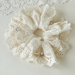 Detail of off-white lace hair scrunchie with ribbons, pearls and sequins