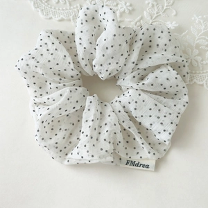 Detailed macro shot of vintage white polka dot scrunchie with lace decorative background