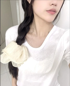 Detail of cream pleated oversized scrunchie worn on a dark braided hairstyle