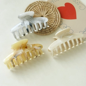 Close-up of elegant marble and tortoiseshell pattern hair claws on a woven mat