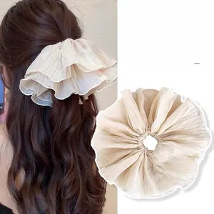 Detail of multi-layered ruffled beige scrunchie with voluminous wavy edge design