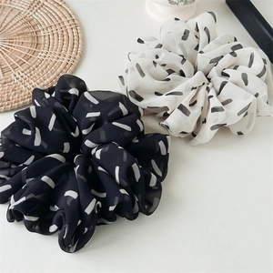 Close-up of black and white striped chiffon oversized scrunchies set on aesthetic backdrop