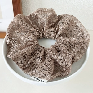 Detail of elegant mesh scrunchie in coffee brown with exquisite woven texture and brand label