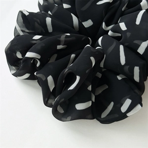Detail shot of the black and white striped chiffon scrunchie with soft pleated texture