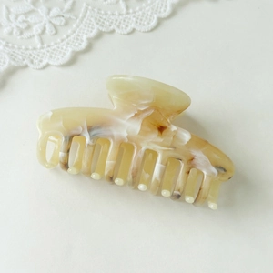 Close-up of elegant cream amber acetate hair claw clip with marble texture and lace detail
