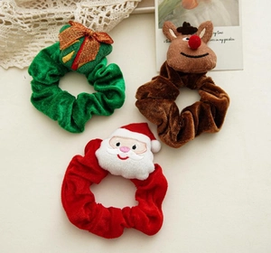 Detail of three plush Christmas scrunchies featuring Santa, reindeer, and gift bow designs