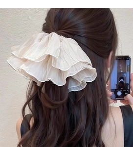 Detailed close-up of cream-white ruffled chiffon scrunchie worn on model's hair