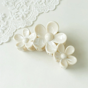 Detail of floral hair claw clip with marble texture and white lace background