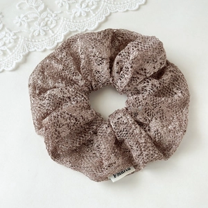 Close-up of elegant bronze lace scrunchie with detailed mesh texture on white background