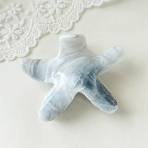 Detail of starfish hair claw clip featuring blue marble texture and glossy finish