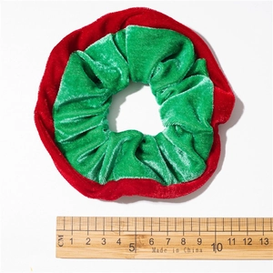 Macro detail of a 10cm red and green velvet Christmas scrunchie on a white background