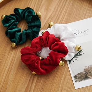 Detail of Christmas velvet scrunchies in red, green and white with gold metal bells