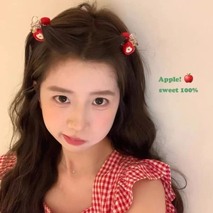 Cute red apple hair clips with white heart motifs worn by a female model in a lifestyle shot