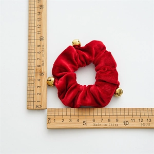 Detail of red velvet Christmas scrunchie with gold bells and measuring scale