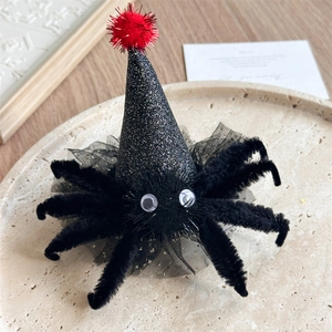 Détail d'une pince à cheveux araignée d'Halloween avec chapeau de sorcière et pompon rouge