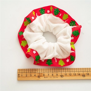 Detail view of red Christmas scrunchie with white plush trim and festive pattern
