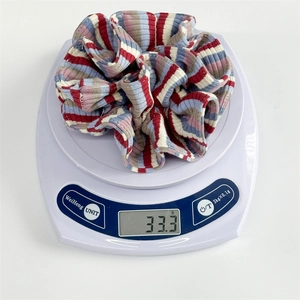 Detail shot of a colorful striped oversized scrunchie weighing 33.3g on a digital scale