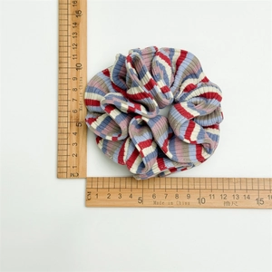 Flat lay of a striped scrunchie on measuring rulers showing its 11cm diameter size